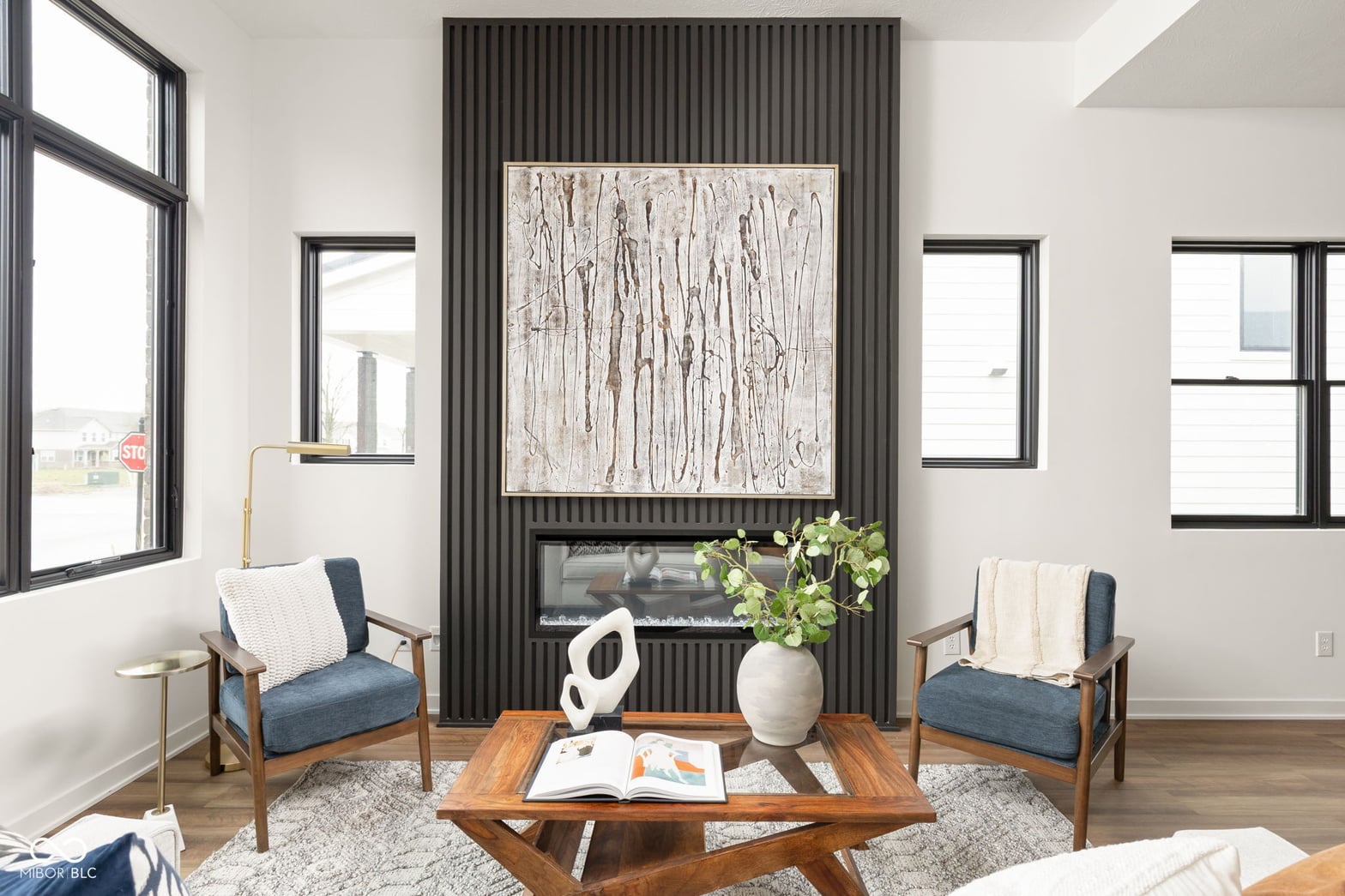 Modern living room with striking fireplace and abundant natural light.