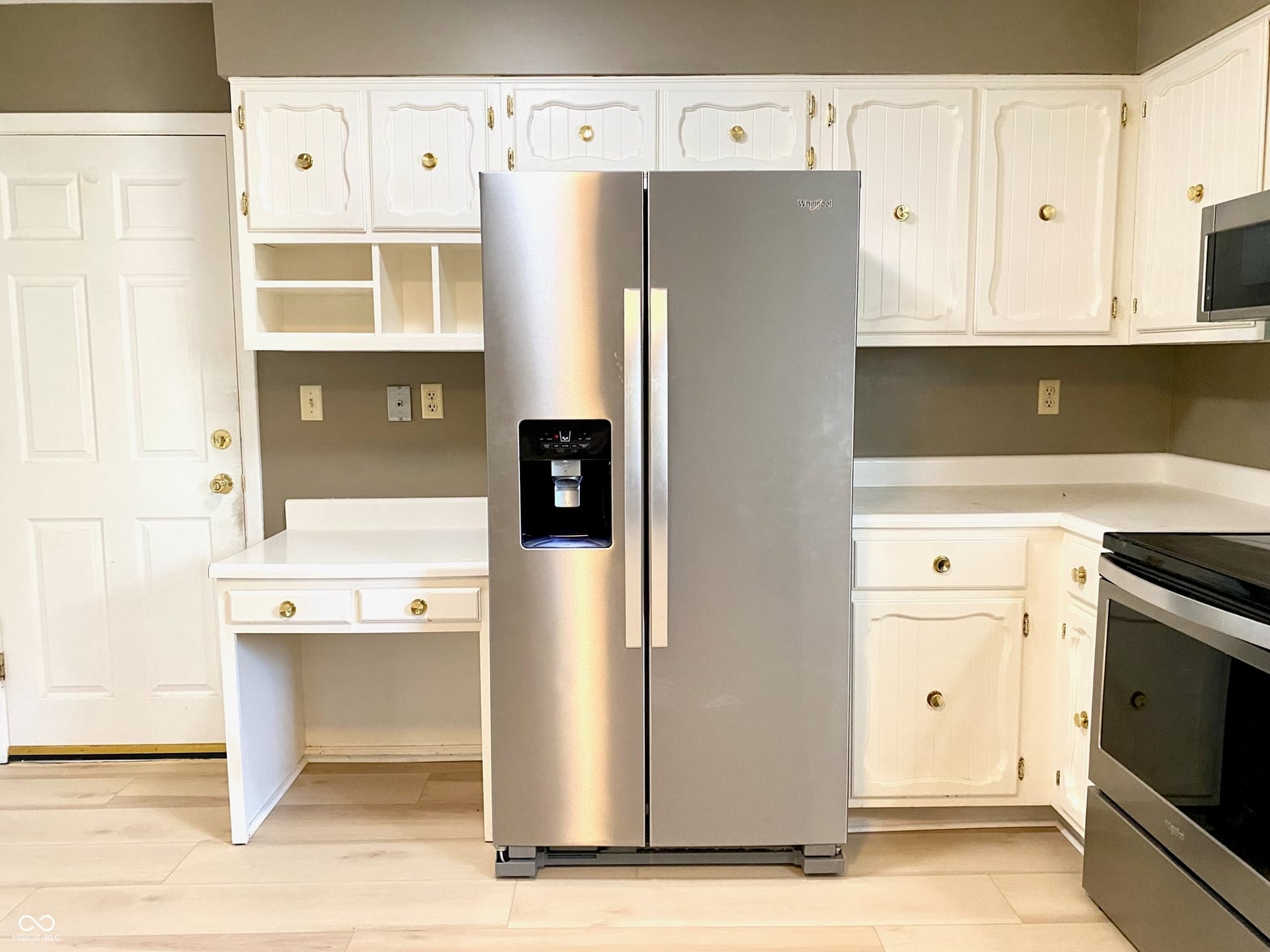 Updated kitchen with stainless steel appliances and white cabinetry.