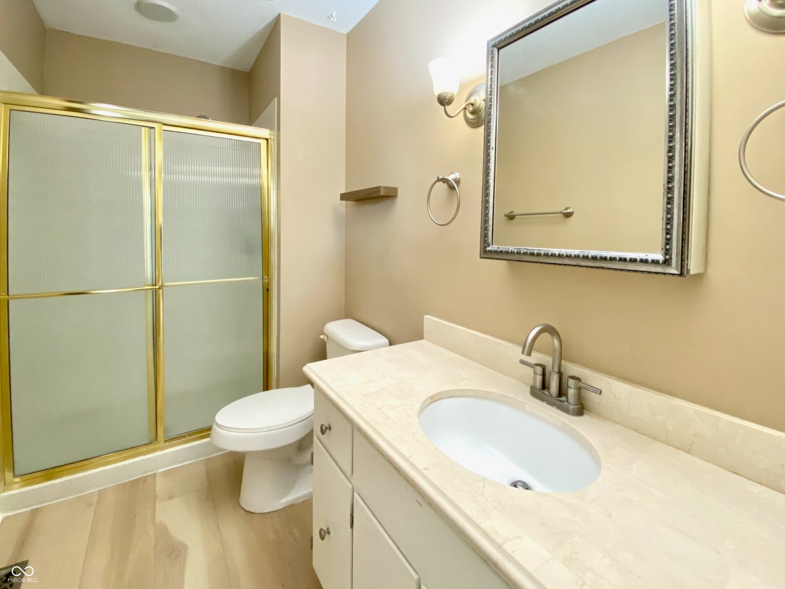Elegant primary bath with marble counters and frameless shower.