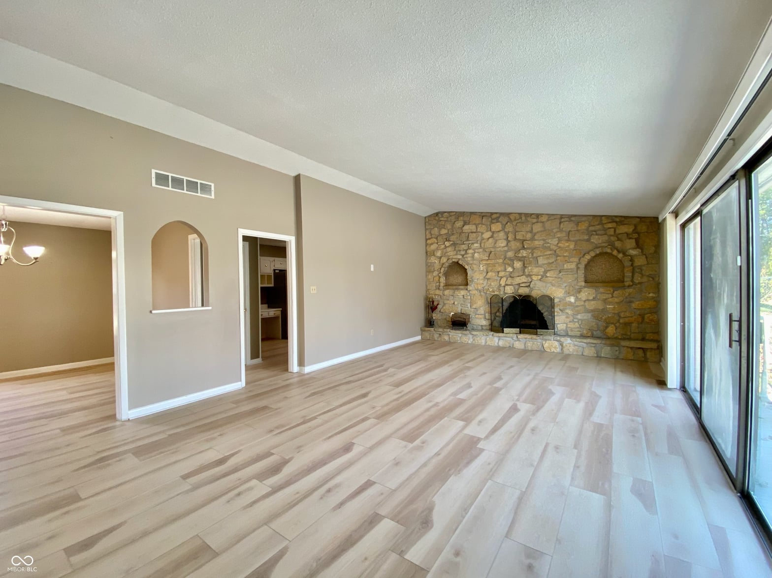 Spacious living area with stone fireplace and hardwood floors.