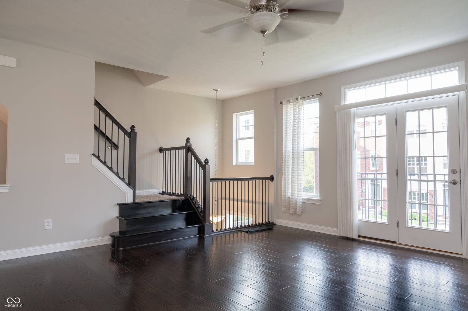 Bright open living space with elegant staircase and French doors.