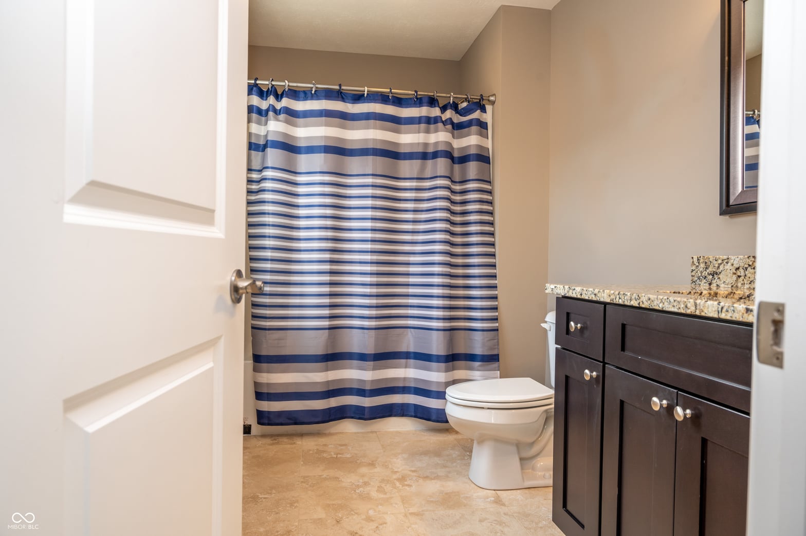 Spacious primary bath with granite counters and dark cabinetry.