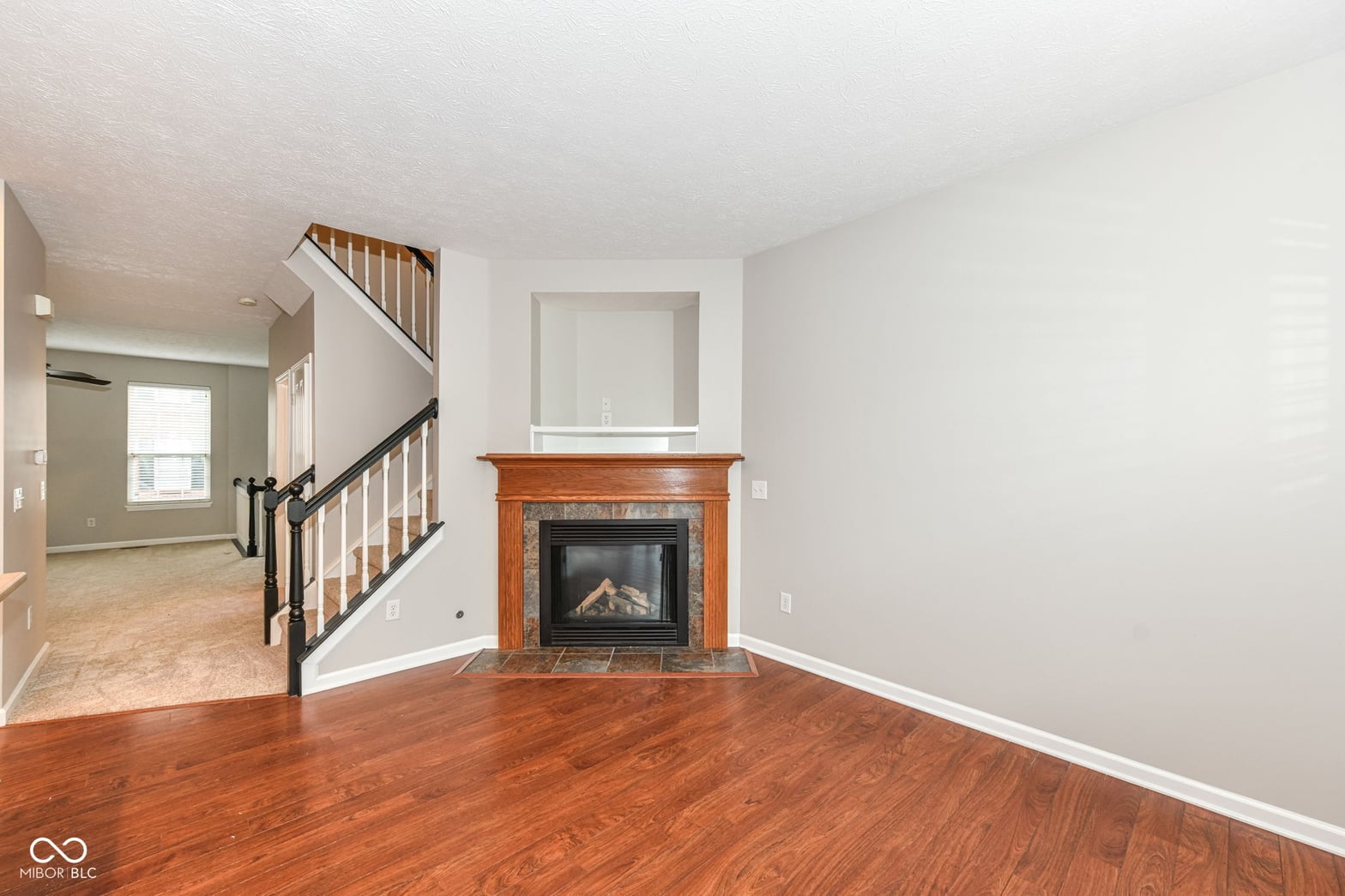 Spacious living room with wood fireplace and hardwood floors.
