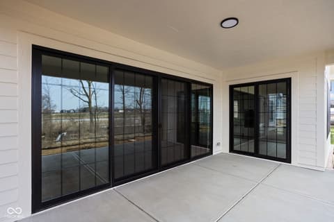 Outdoor living area at 16956 Tractive Drive, Westfield, IN — Expansive black-frame glass doors open to covered patio.