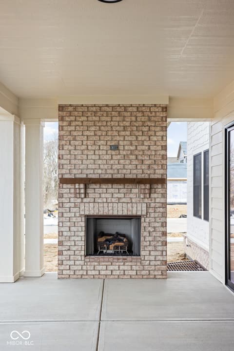 Outdoor living area at 16956 Tractive Drive, Westfield, IN — Brick fireplace on covered patio with modern amenities.