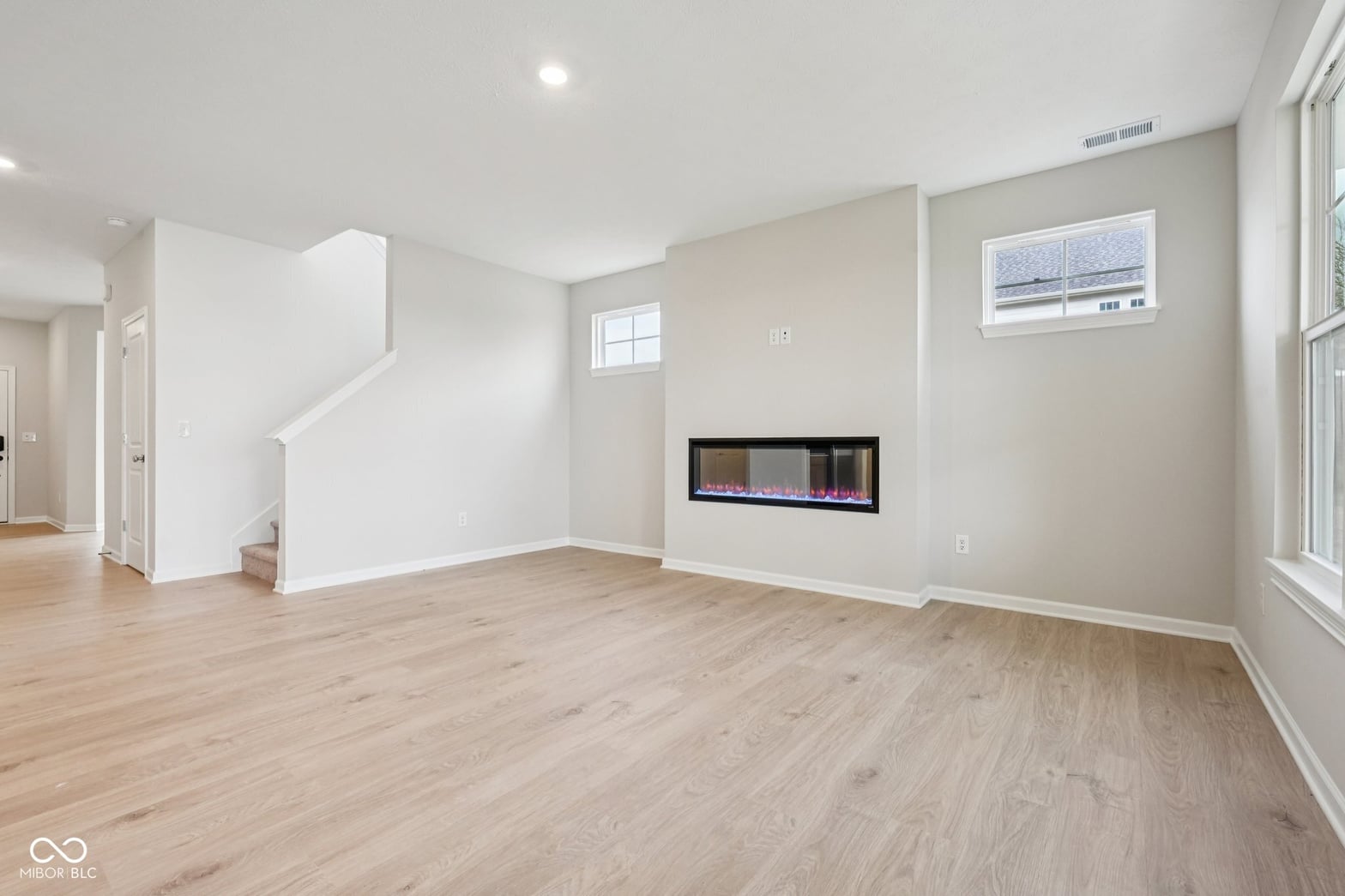 Modern family room with electric fireplace and hardwood floors.