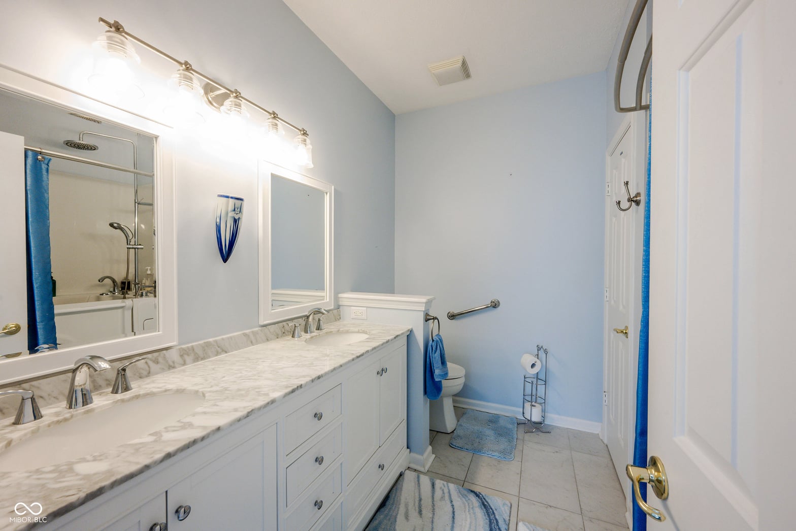 Spa-like primary bath with marble counters and double vanity.