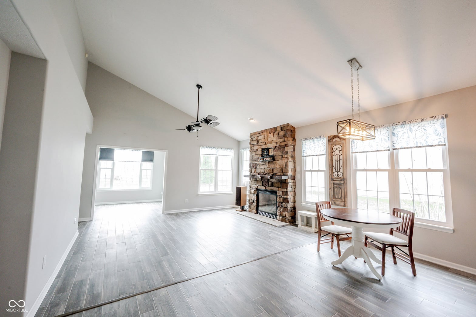 Bright open living space with stone fireplace and abundant windows.