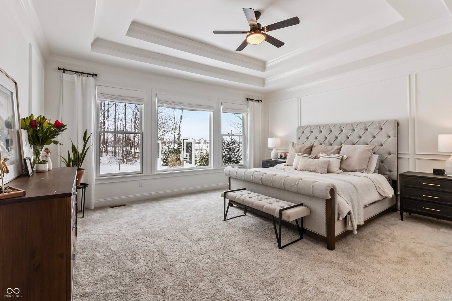 Bright primary bedroom with coffered ceiling and bay windows.