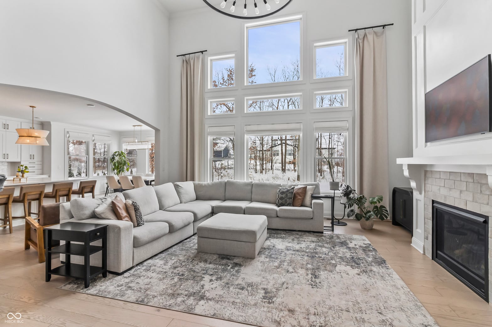Bright open living room with soaring windows and fireplace.