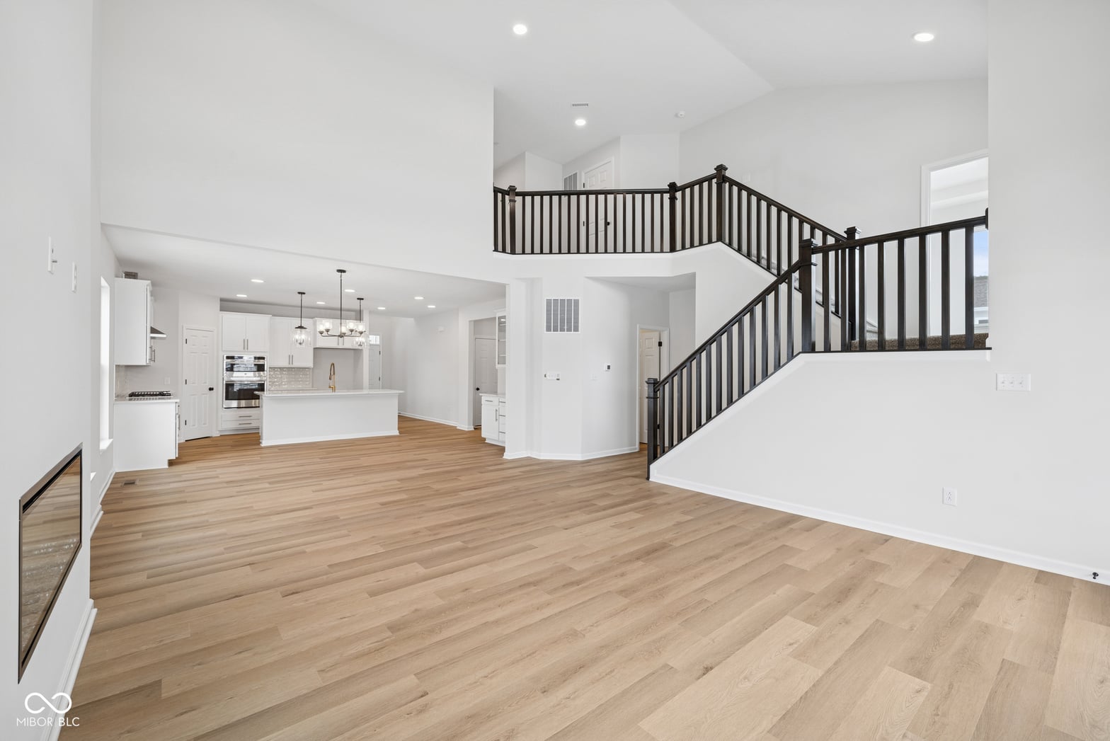 Spacious open concept with elegant curved staircase and hardwood floors.
