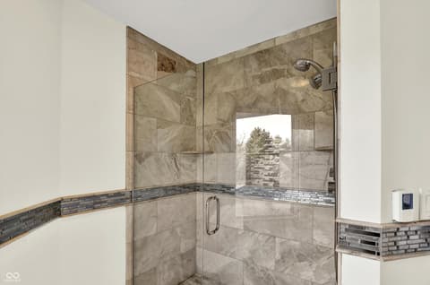 Primary bathroom at 434 Sheffield Court, Carmel, IN — Luxurious frameless marble shower with rainfall head.