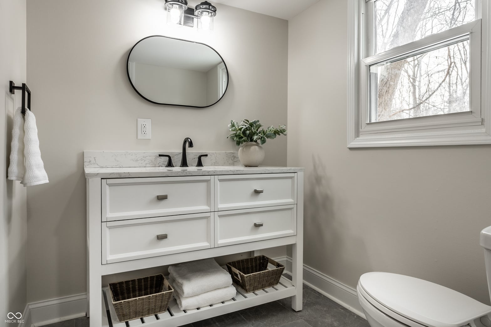 Bright modern bathroom with marble counters and storage.
