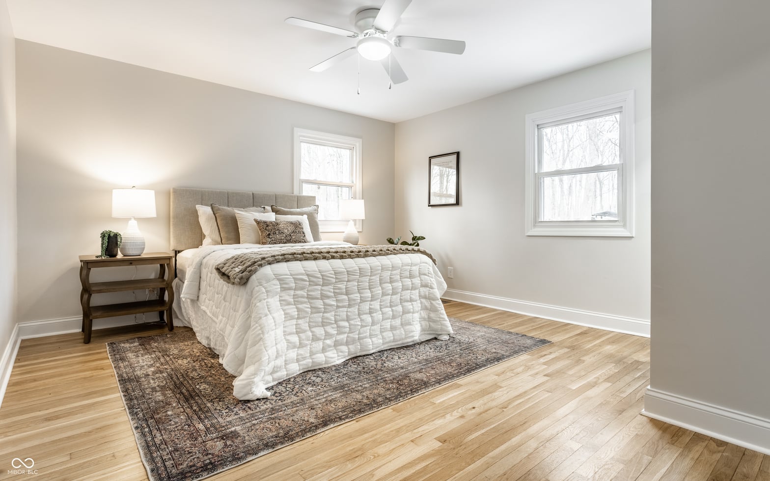 Bright primary bedroom with hardwood floors and dual windows.