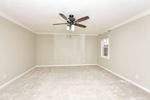 Bedroom at 13035 Wembly Road, Carmel, IN — Spacious bedroom with elegant crown molding and ceiling fan.