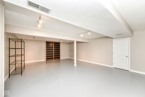 Basement at 13035 Wembly Road, Carmel, IN — Spacious finished basement with epoxy flooring and storage.