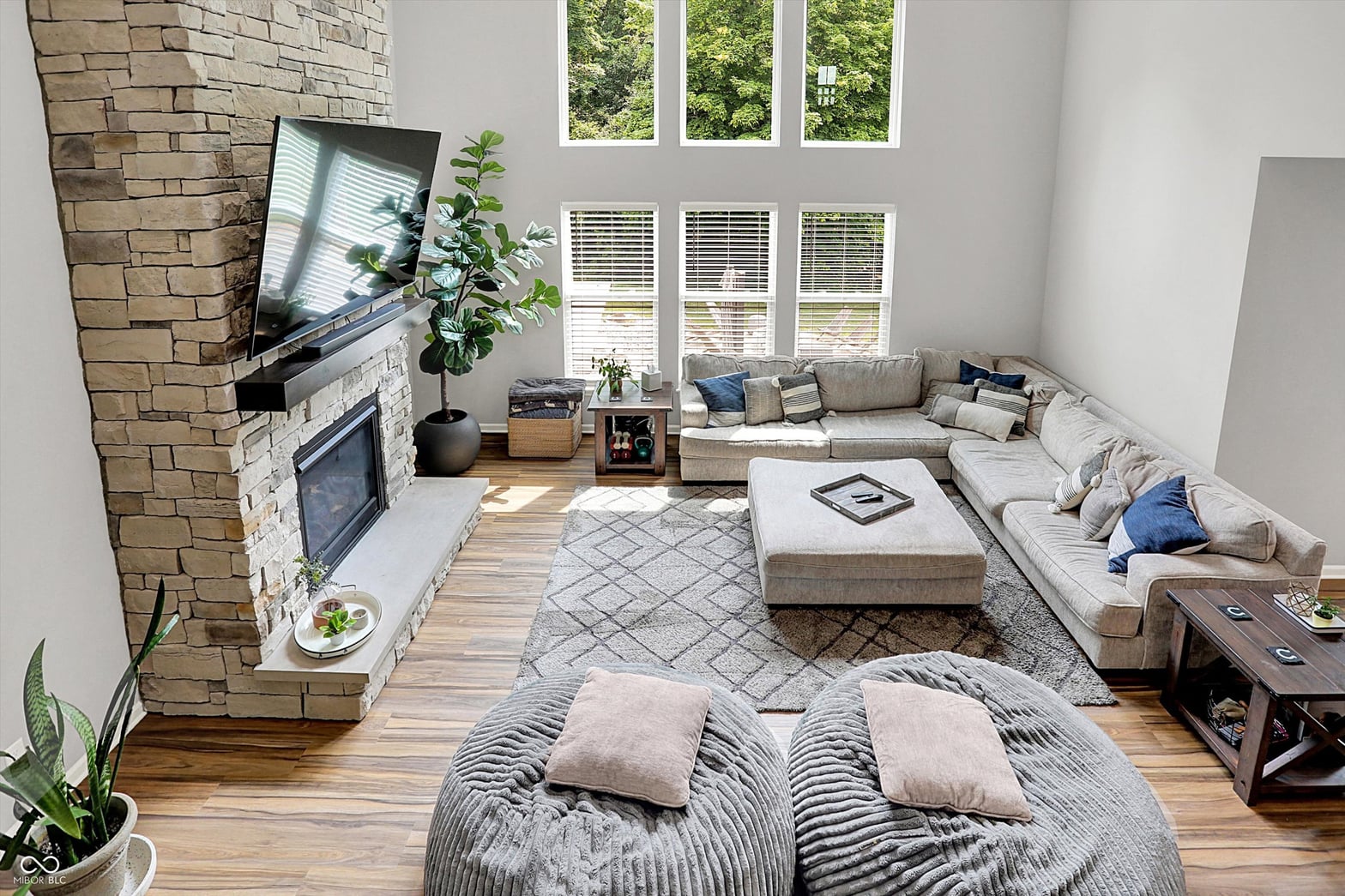Bright contemporary living room with stone fireplace and ample windows.