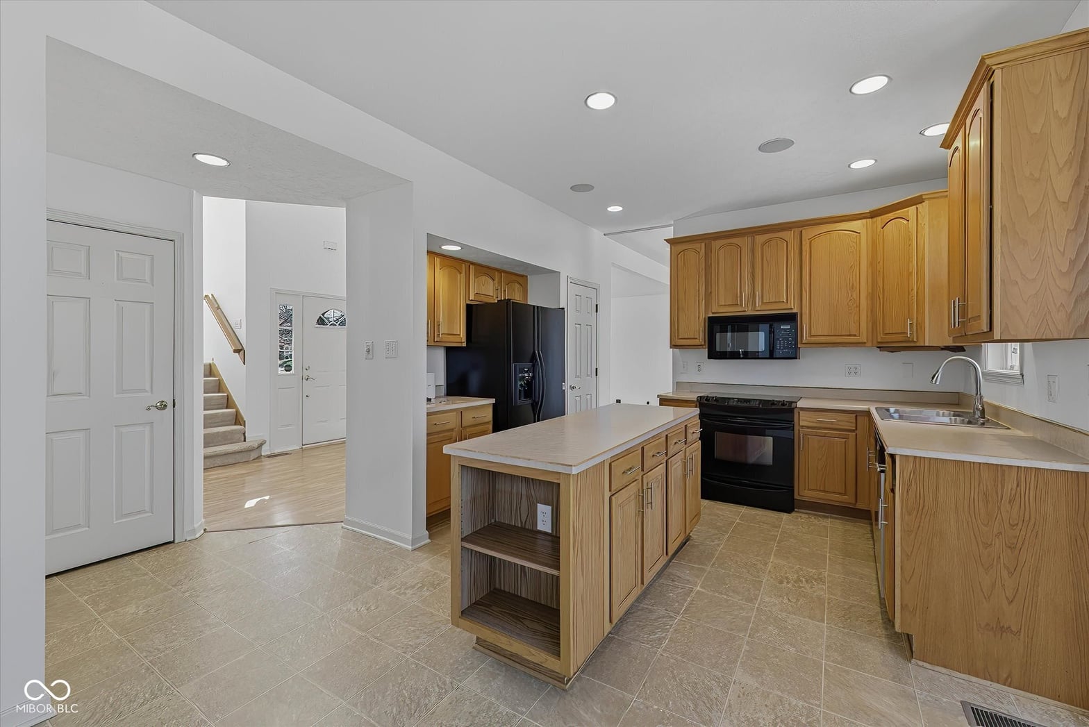 Spacious kitchen with oak cabinets and black appliances.