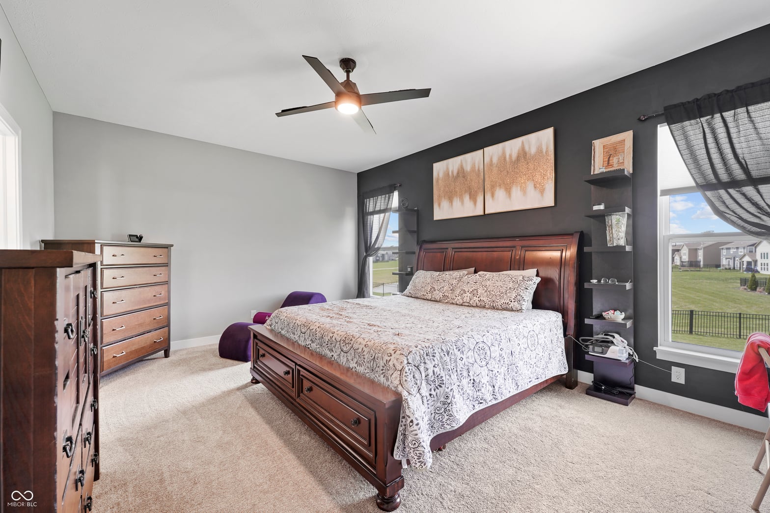 Spacious primary bedroom with accent wall and abundant windows.