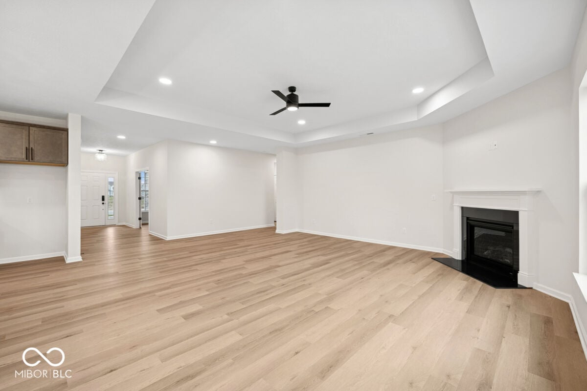 Spacious family room with modern tray ceiling and fireplace.