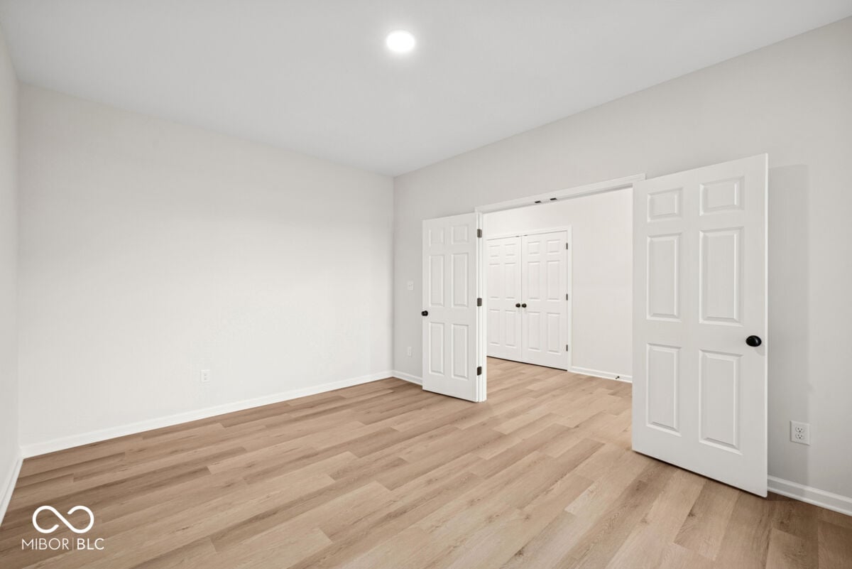 Bright primary bedroom with walk-in closet and hardwood floors.