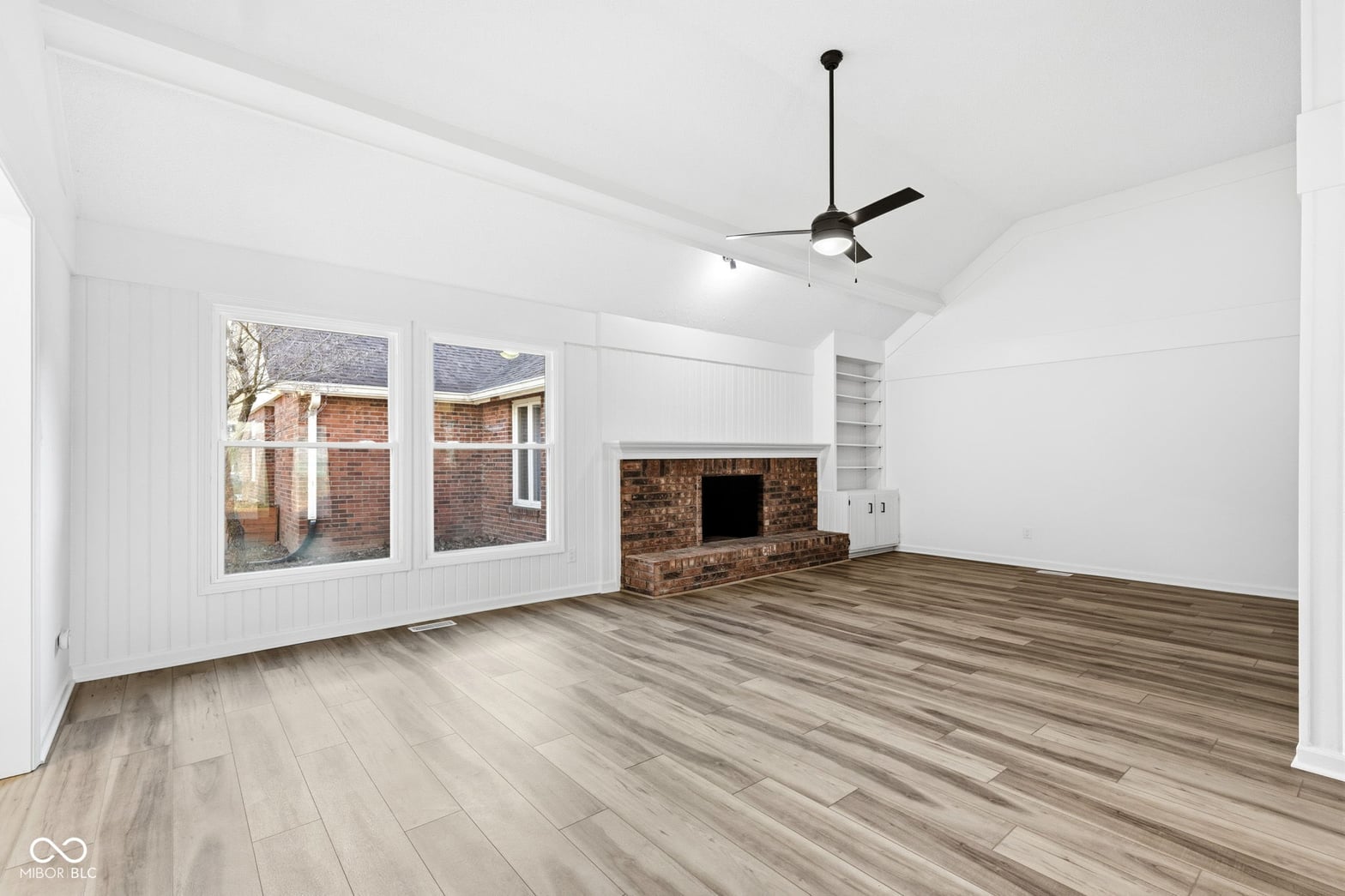 Bright renovated family room with fireplace and hardwood floors.