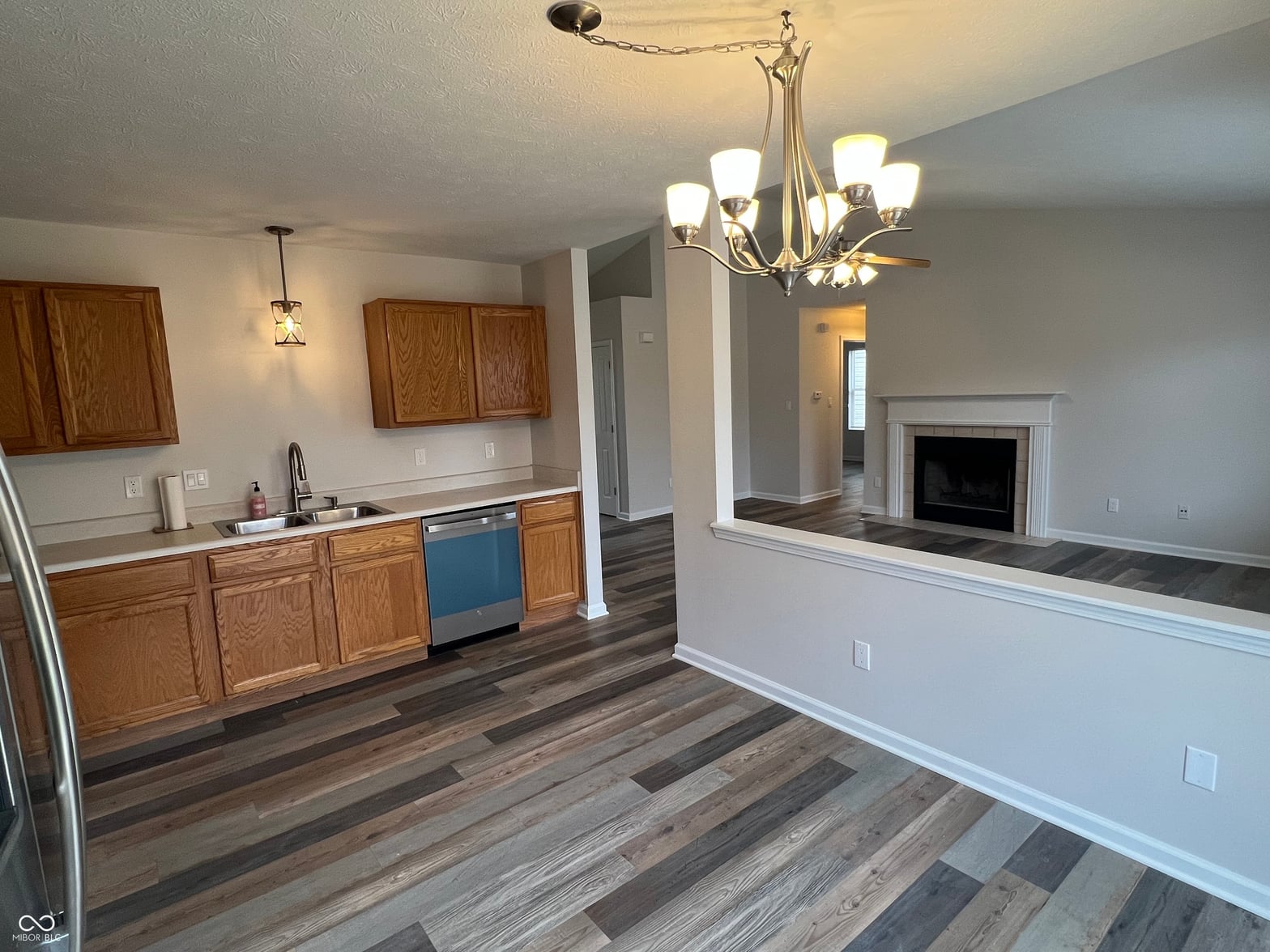 Open concept kitchen with hardwood floors and fireplace.
