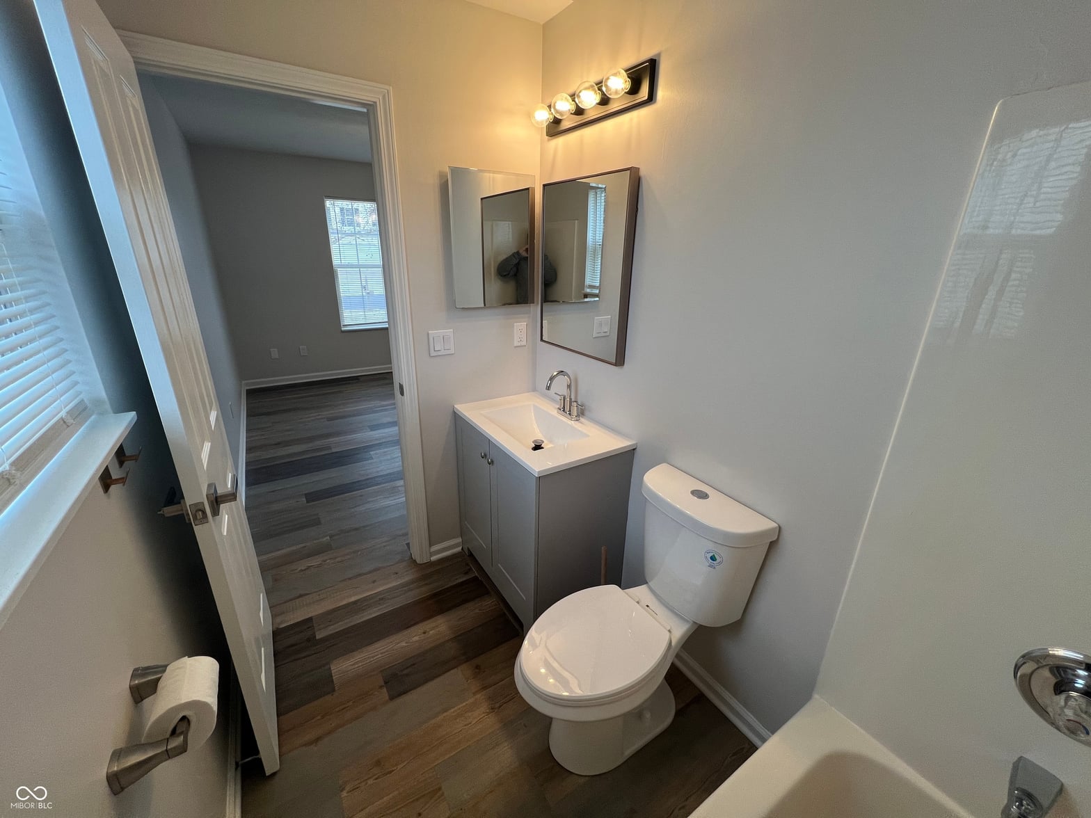 Modern renovated primary bathroom with hardwood floors.