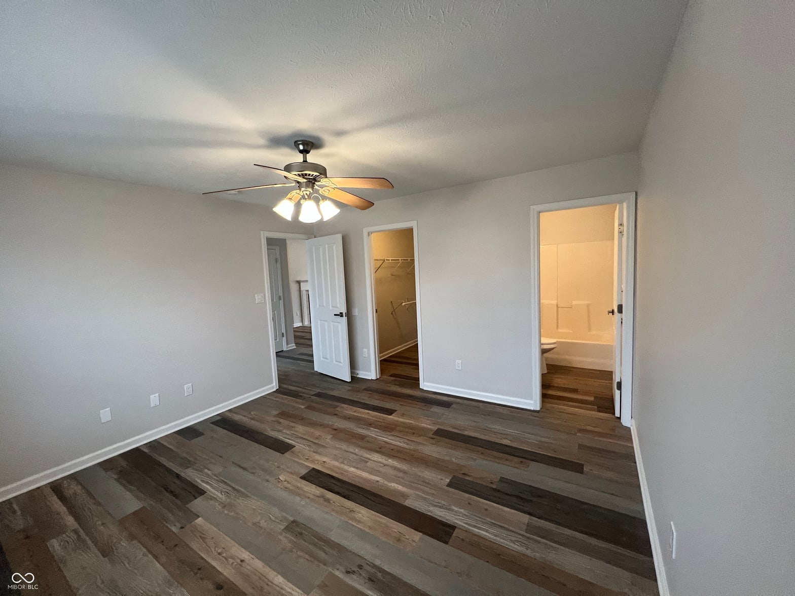 Spacious primary bedroom with hardwood floors and multiple closets.