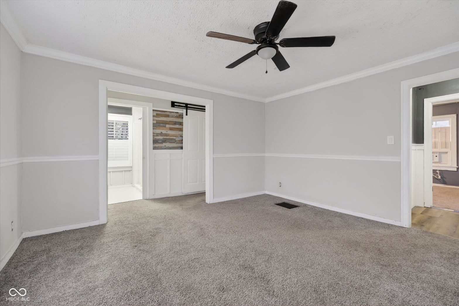 Spacious primary bedroom with updated wainscoting and neutral finishes.