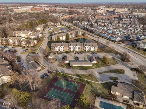 Aerial view at 12517 Timber Creek Drive, Carmel, IN — Modern multi-unit complex with tennis courts and pond views.