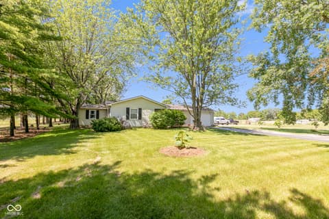 Front exterior at 8440 E 216th Street, Cicero, IN — Charming home on tree-lined lot with mature landscaping.