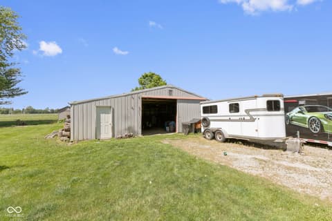 Side exterior at 8440 E 216th Street, Cicero, IN — Spacious rural property with metal garage and RV storage.