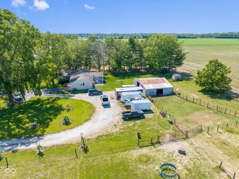 Aerial view at 8440 E 216th Street, Cicero, IN — Scenic rural farmstead with barns and fenced pastures.