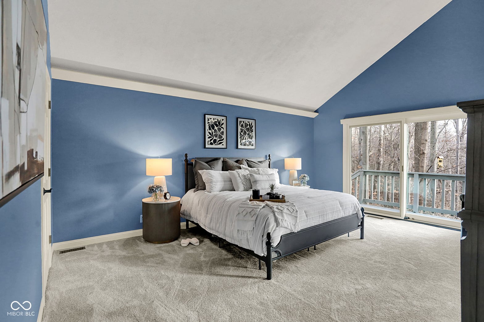 Spacious primary bedroom with scenic forest views and balcony.