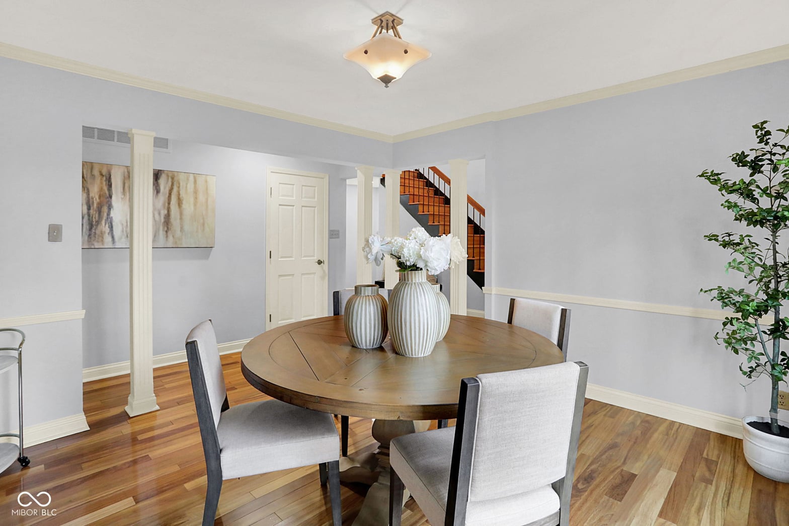 Light-filled dining room with hardwood floors and wainscoting.
