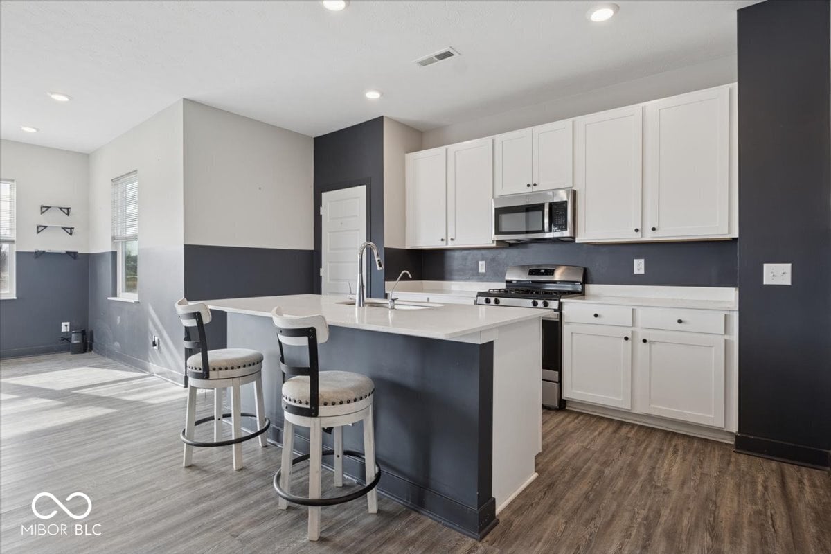 Modern kitchen with white cabinetry and dark accent wall.