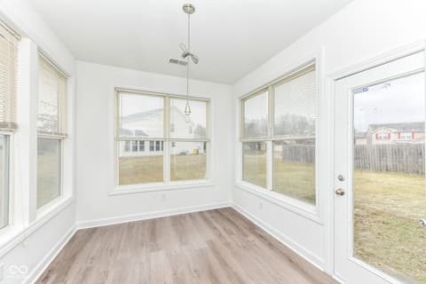 Outdoor living area at 11035 Cool Winds Way, Fishers, IN — Bright sunroom with expansive windows overlooking yard.