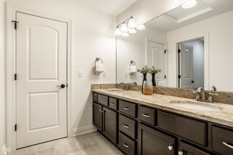 Primary bathroom at 13429 Boxelder Court, Carmel, IN — Spacious dual vanity bath with travertine counters.