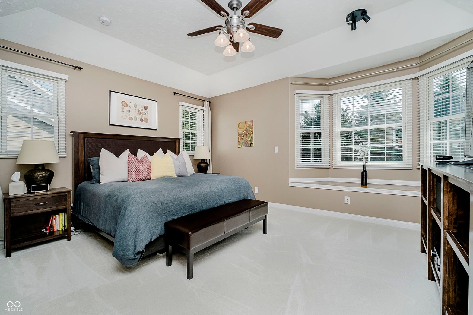 Spacious primary bedroom with abundant natural light and bay windows.