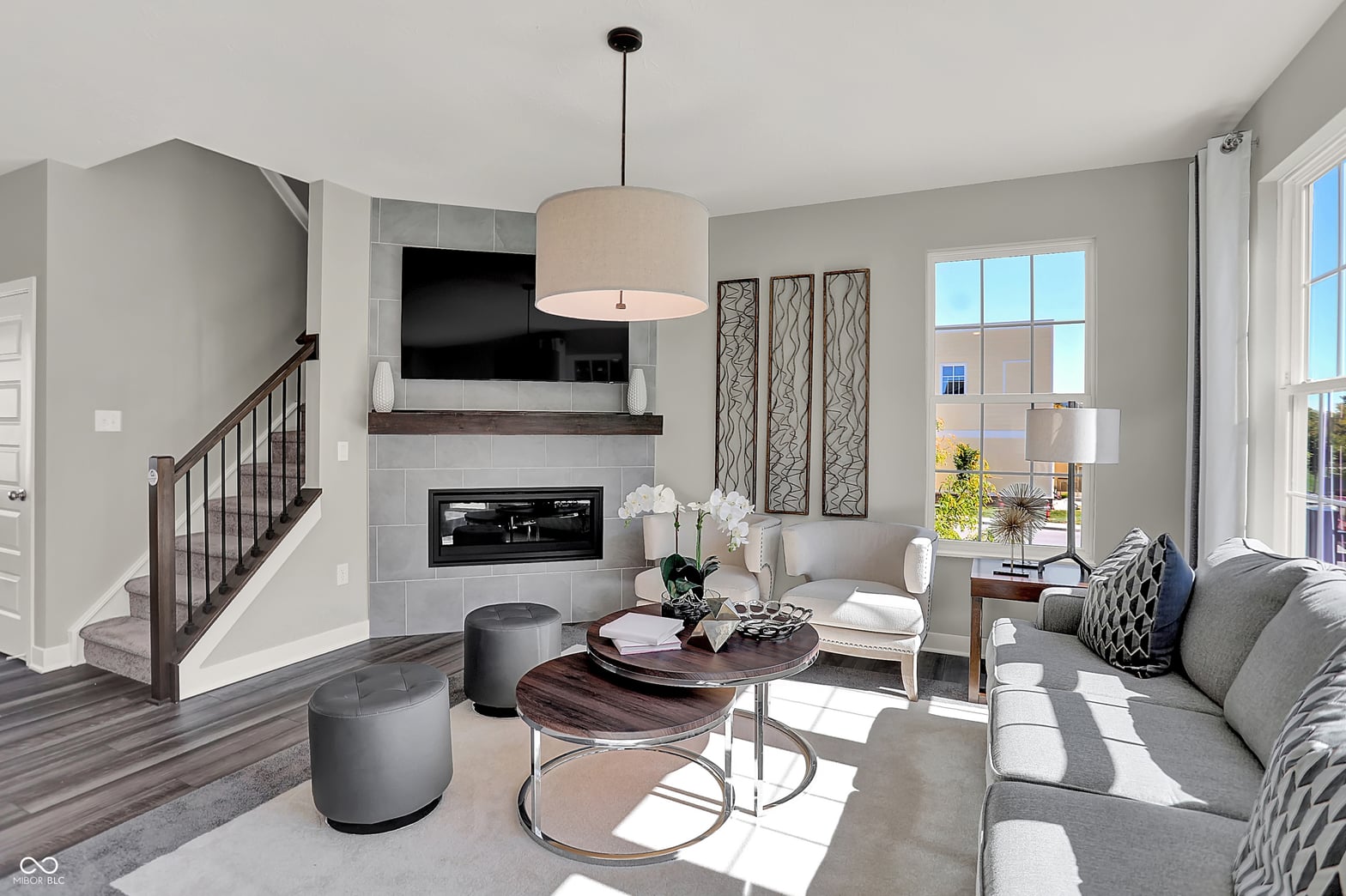 Bright modern living room with fireplace and open staircase.