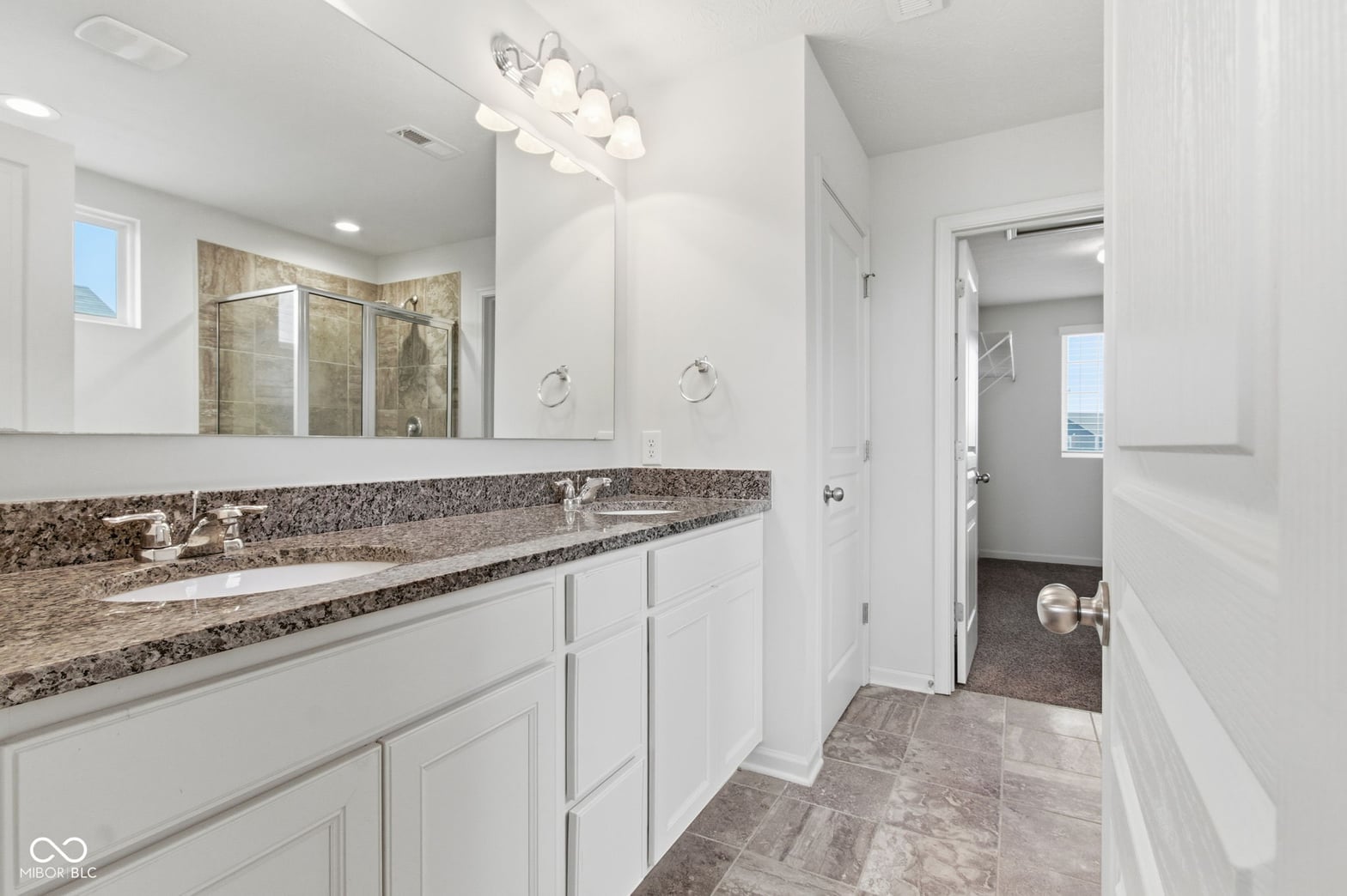 Luxurious primary bath with granite countertops and frameless shower.