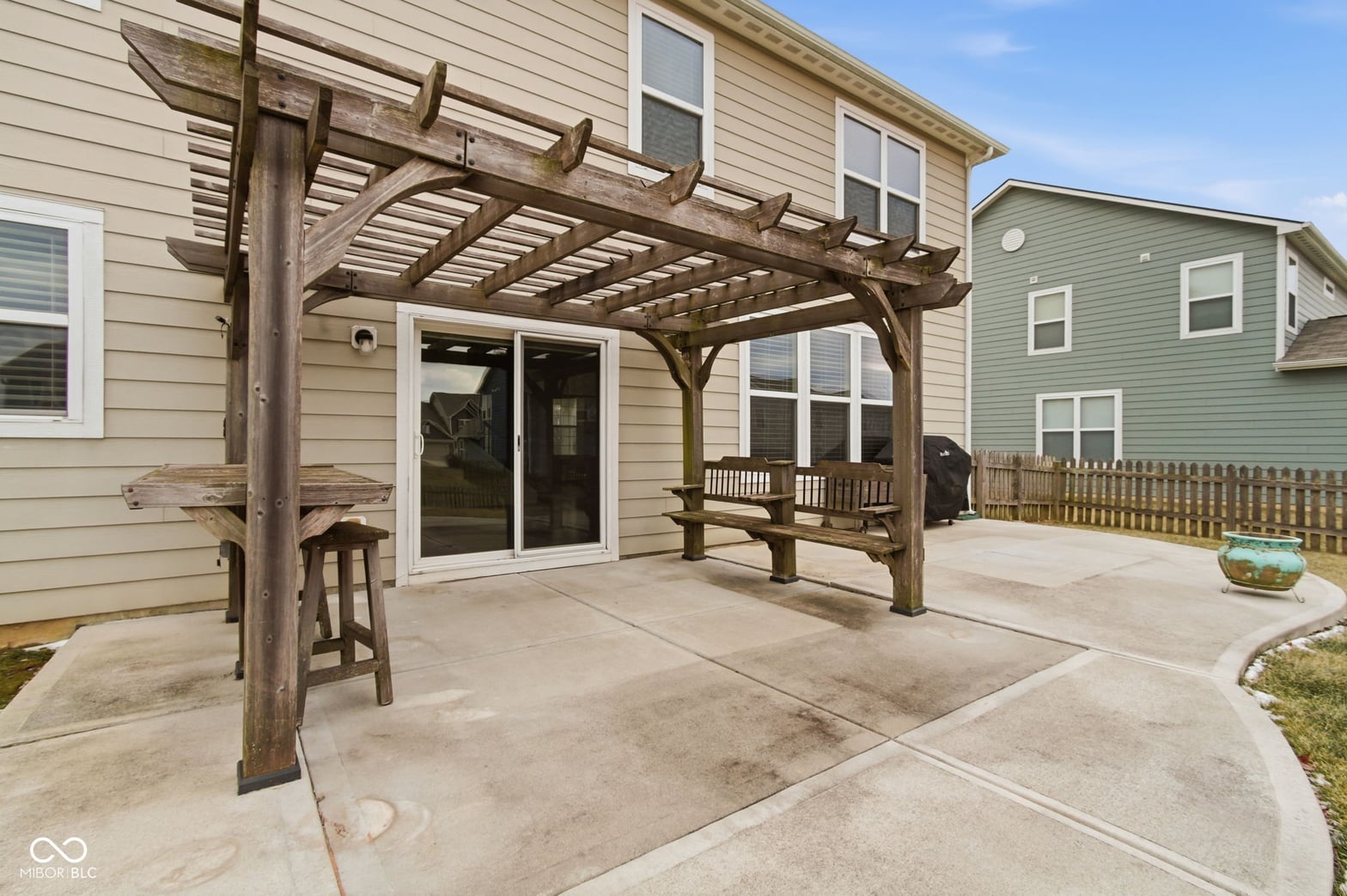 Spacious patio with rustic wood pergola and shade.