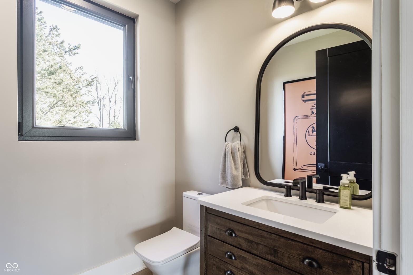 Contemporary primary bath with statement mirror and quartz counters.