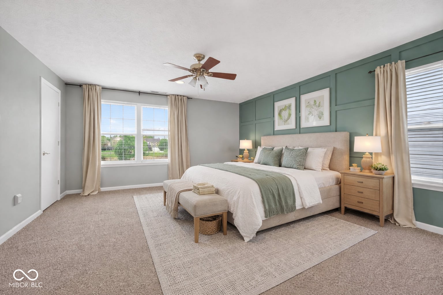 Bright primary bedroom with sage accent wall and ample windows.
