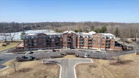 Aerial view at 20971 Shoreline Court, Noblesville, IN — Modern multi-unit brick complex with scenic pond views.