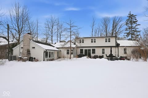 Front exterior at 1025 Oswego Road, Carmel, IN — Modern farmhouse on expansive snowy lot with mature trees.