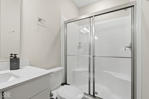 Primary bathroom at 15546 Senita Lane, Fishers, IN — Sleek modern bathroom with frameless glass shower enclosure.