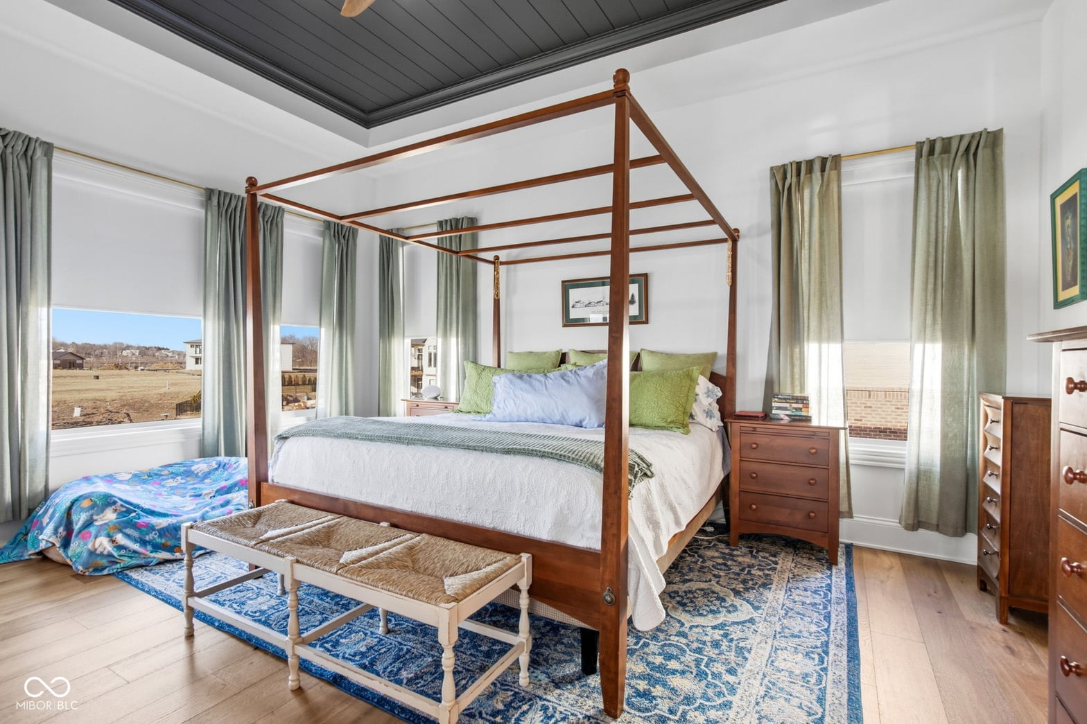 Bright primary bedroom with four-poster canopy bed and countryside views.