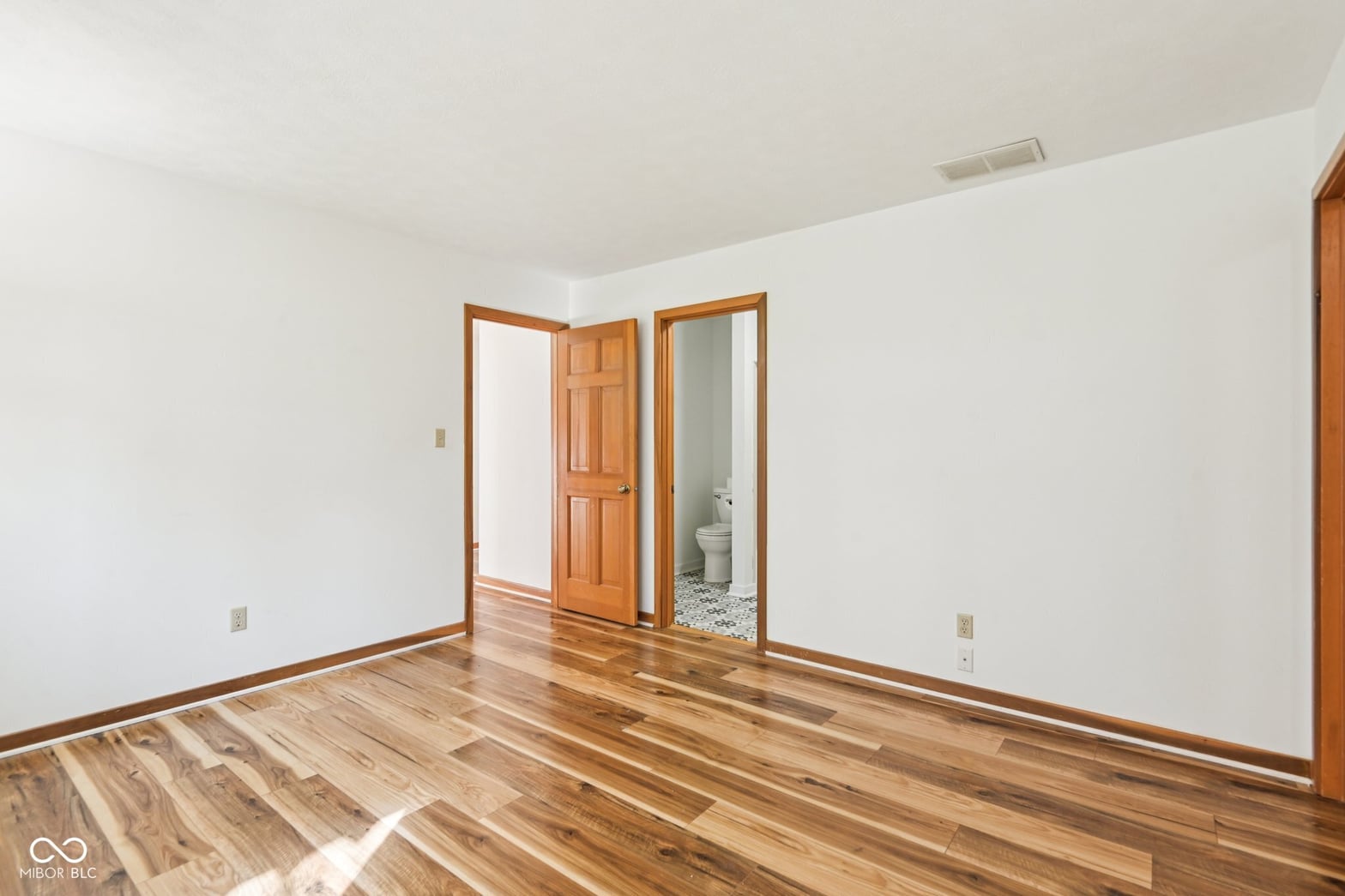 Spacious primary bedroom with ensuite and hardwood floors.